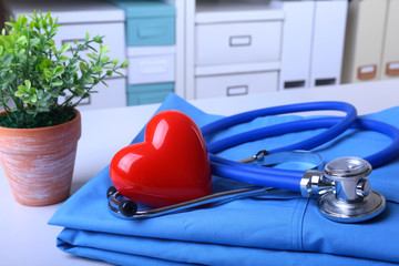 Doctor coat with medical stethoscope and red heart on the desk