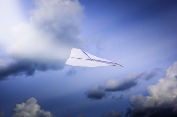 Aeroplano di carta che vola in cielo tra le nuvole