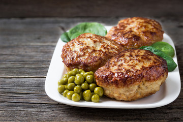 Homemade cutlets   with green peas on a plate in a rustic style.
