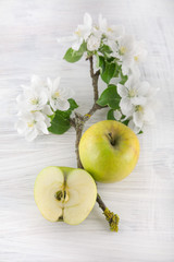 freh ripe green apple decorated with beautiful apple blossom on white wooden table, rustic food...