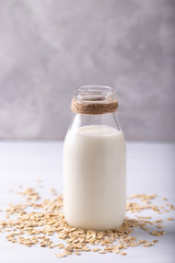 Obraz na płótnie Canvas Vegan non dairy oat milk and flakes on white wooden background
