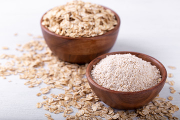 Vegan non dairy oat milk and flakes on white wooden background