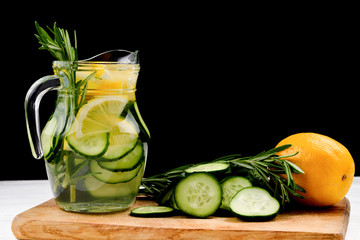 Cold and refreshing detox water with lemon, cucumber, rosemary and ice in glass jar. Copyspace. Banner