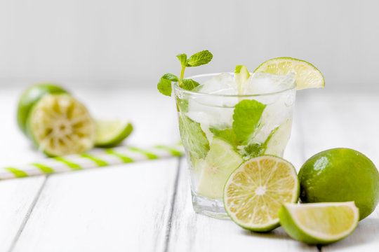 Summer refreshing cocktail mojito with lime and mint on white wooden vintage background.