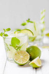 Summer refreshing cocktail mojito with lime and mint on white wooden vintage background.