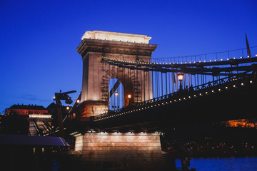 Obraz premium Night view of a famous Budapest Szechenyi Chain Bridge, a suspension bridge that spans the River Danube between Buda and Pest, the western and eastern sides of Budapest