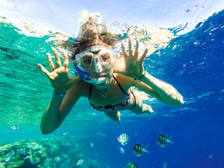 Happy family, girl in snorkeling mask dive underwater with fishes in coral reef sea. Travel...