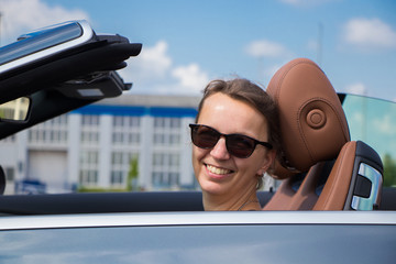 portrait of a beautiful smiling Brunette Woman Driving in Luxury Convertible Sports Car