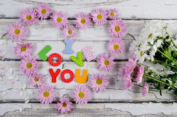 Drewniana tablica na niej tekst kocham Cię i kwiatowe serce