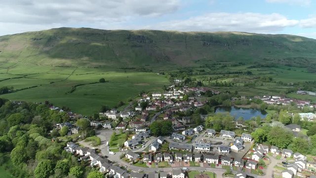 Aerial footage over the village pond at Lennoxtown beneath the Campsie Fells.