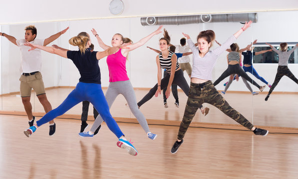 Group of positive smiling teenagers dancing   in classroom