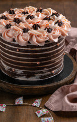 Chocolate birthday cake with roses served on wooden background