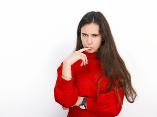 Young beautiful brunette woman in red sweater showing suspicious emotion posing against white background