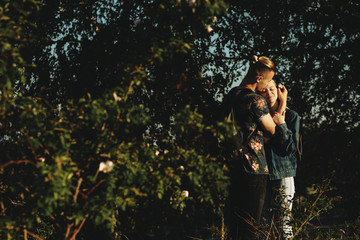 Amazing caucasian couple traveling where man is puting a flower in his girlfriend's hair in their resting time, while she embracing him with closed eyes and smiling.