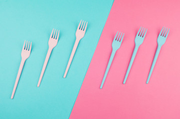 Pink and blue painted forks on the same colors background. Abstract artistic concept.