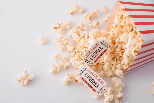 Popcorn and movie tickets on white table top view