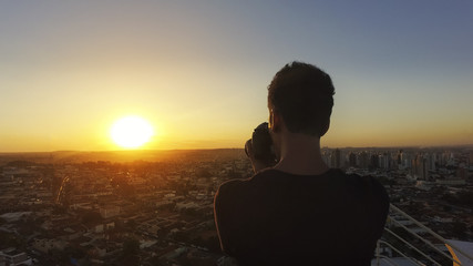 Silhouette of a photographer taking pictures on top of the building at sunset