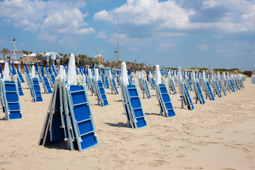 Sand beach with blue sun loungers in summer day
