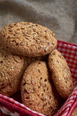 homemade oat cookies with sunflower seeds in and near red checkered basket on wooden table