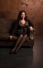 Fototapeta na wymiar Stunning mature woman in fashionable apparel posing in the dark room