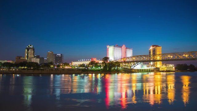 Shreveport LA Cityscape Night Timelapse with Lights from Skyscrapers and Casinos Reflecting onto the Moving Red River on a Blue Sky Background