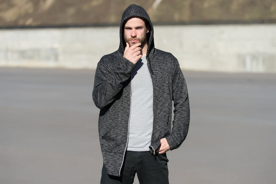 Bearded man wear casual sweatshirt outdoor. Guy touch beard on sunny day. Fashion macho in stylish sportswear. Lifestyle for active and healthy man. Skincare and barber salon