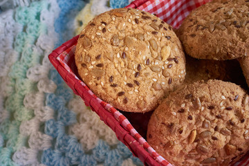homemade oat cookies with sunflower seeds in and near red checkered basket on white and blue plaid