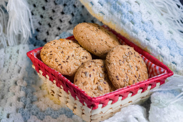 homemade oat cookies with sunflower seeds in and near red checkered basket on white and blue plaid