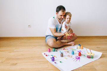 Father and little boy of fivr years having fun painting at home