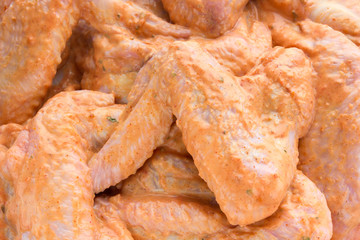Marinated chicken wings close-up. A bunch of marinated chicken wings scattered over the surface.