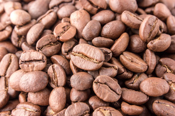 Coffee grains are scattered all over the surface. Roasted coffee beans close-up.