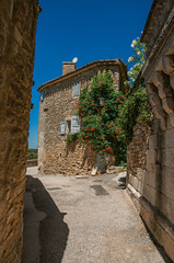 Fototapeta na wymiar View of typical stone houses with sunny blue sky and flowers, in an alley of the historical village of Menerbes. In the Vaucluse department, Provence-Alpes-Côte d'Azur region, southeastern France