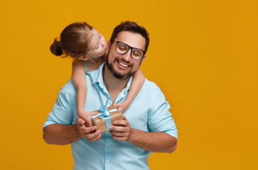 happy father's day! cute dad and daughter hugging on yellow background.