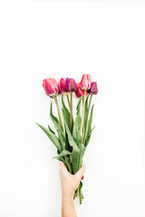 Woman hand holding tulips bouquet on white. Flat lay, top view flowers festive background.