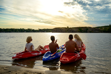 Obraz premium Friends Paddling Kayaks on the Beautiful River or Lake under Dramatic Evening Sky at Sunset