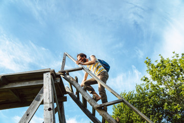 Junger Mann klettert auf einen Hochsitz