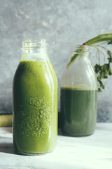 Healthy green smoothie with kale banana and date in glass bottles against a dark background. Detox, diet, healthy, vegetarian food concept with copy space.