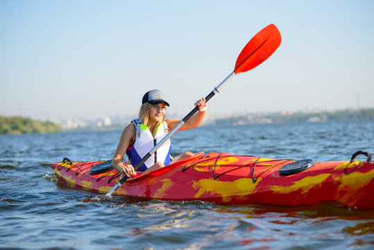 Young Professional Woman Kayaker Paddling Kayak on River under Bright Morning Sun. Sport and Active Lifestyle Concept