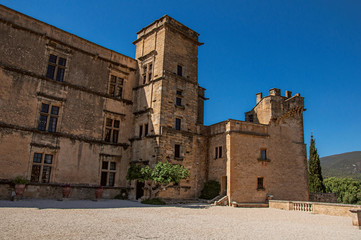 Fototapeta premium Panoramic of the courtyard and Castle facade of Lourmarin with hills in the background, near the village of Lourmarin. In Vaucluse department, Provence-Alpes-Côte d'Azur region, southeastern France