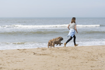 A girl and dogs run along the seashore