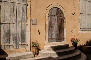 Fototapeta na wymiar View of colorful house and door with flowers and steps, on a street of the historical village of Lourmarin. Located in the Vaucluse department, Provence-Alpes-Côte d'Azur region, southeastern France