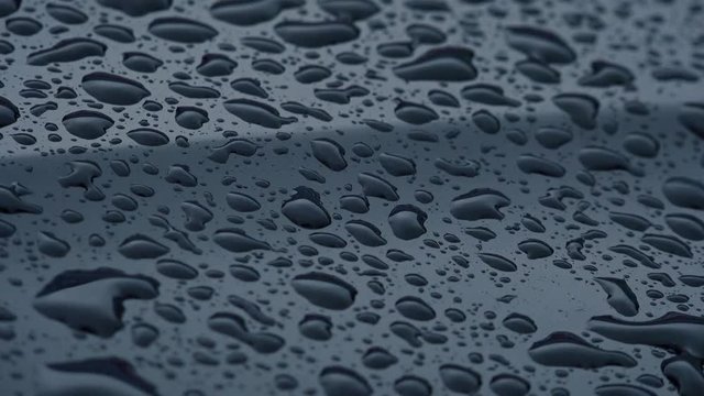 Close-up View of Rain Drops Drips Down on Black Surface. 4K Ultra HD