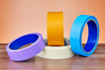 Multicolored rolls of colored scotch on an orange background.