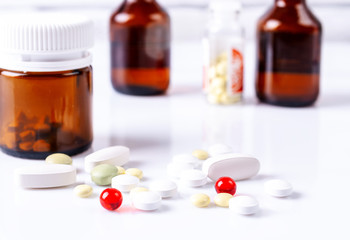 Pills and medical bottles on a white table.