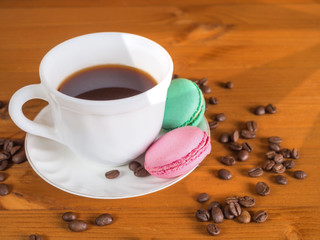 Cup with coffee, cakes and coffee beans on a wooden background