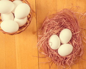 Wooden basket with eggs and chicken nest on a wooden background