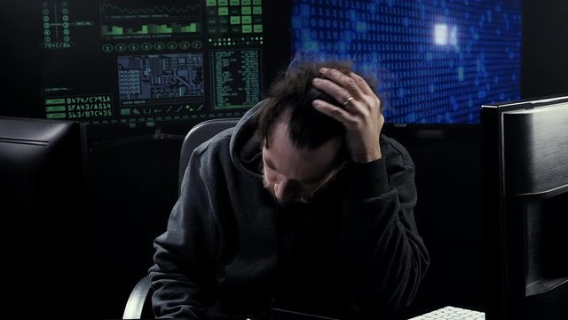 Sad desperate man working at night in front of pc coding unhappy