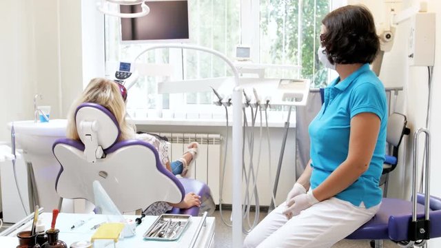 4k video of dentist sitting with patient during teeth whitening procedure