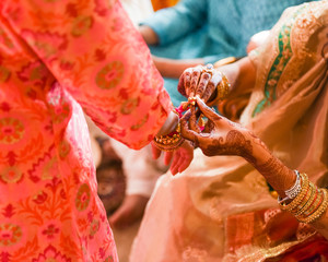 traditional Indian Hindu bride with henna putting bracelet on
