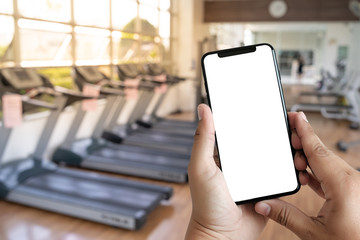 Young man Hand holding smartphone in gym to  fitness phone fitness exercise concept